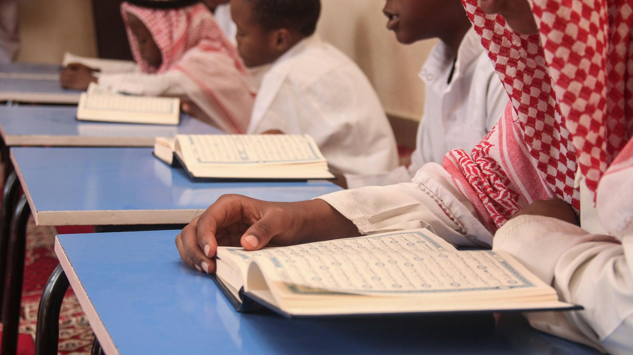 Boys engaging in reading religious texts at a school during study hours.